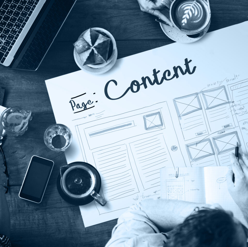 Vrouw gebogen over blad met content schema op, met een tas koffie, gsm, en laptop in de buurt.
